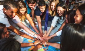 youth thriving, Six reasons to read Teen Centered Civics for Human Thriving_feature: group of teens put hands together over world map