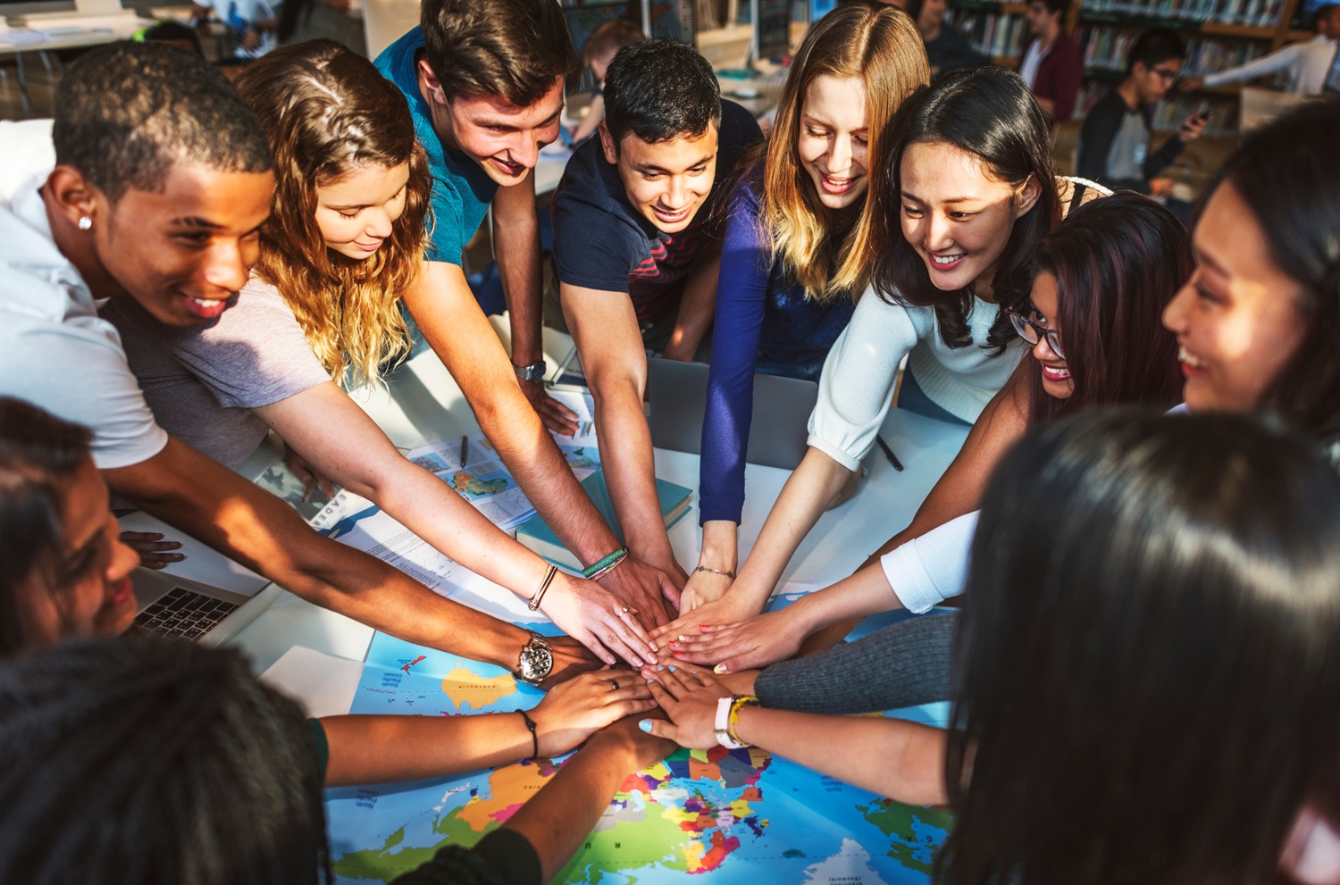 youth thriving, Six reasons to read Teen Centered Civics for Human Thriving_feature: group of teens put hands together over world map
