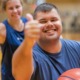 Back to school back to Unified_How your organization can champion inclusion_feature: Young adult with down syndrome smiling and giving a thumbs up while holding a basketball while another person does the same behind