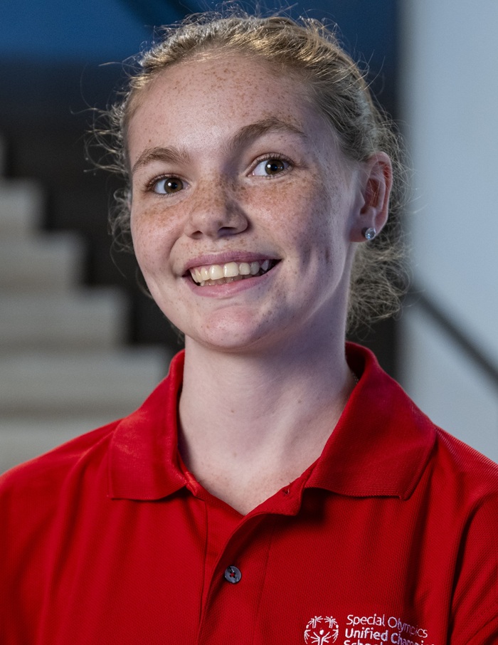 لقطة رأس كاثرين جاكسون: امرأة بيضاء شابة ذات نمش وشعر مرفوع وترتدي قميصًا بياقة حمراء