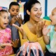 College students can help close the gap between demand and availability for afterschool programs_feature: young woman with group of excited young children around model volcano in afterschool program