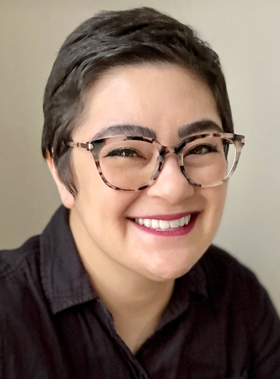 Mariko Yoshisato Cavey headshot: woman with short dark hair and large rimmed glasses in black button up shirt