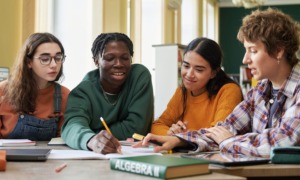 An invitation to learn reflect and act together for equity-centered thriving: group of diverse youth happily works at table together