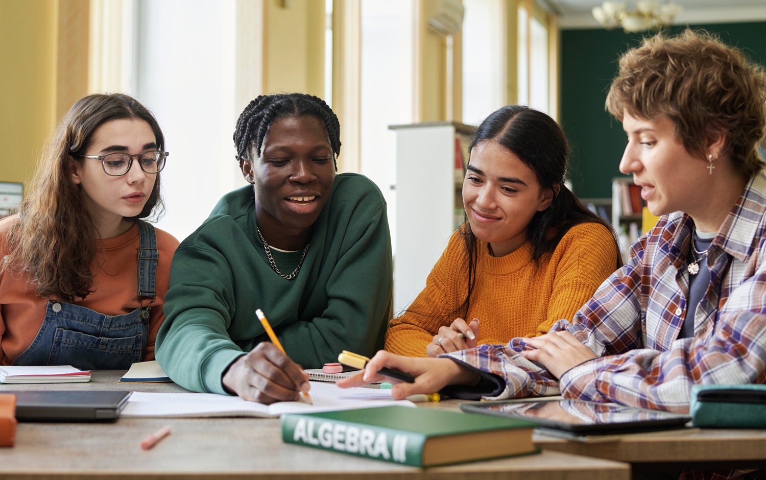 An invitation to learn reflect and act together for equity-centered thriving: group of diverse youth happily works at table together