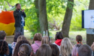 From systems leadership to learning ecosystems stewardship_feature: group of kids watch an educator giving a presentation outside