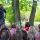 From systems leadership to learning ecosystems stewardship_feature: group of kids watch an educator giving a presentation outside