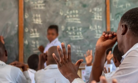 Grants to support and educate youth combatants, youth associated with non-state armed groups: male student raises hand in developing country classroom