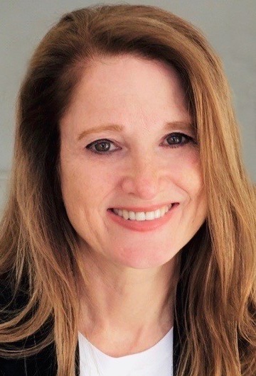 صورة كيم سابو فلوريس: امرأة بيضاء ذات شعر طويل ترتدي سترة وقميصًا أبيض