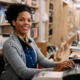Library support, professional and workforce development program grants: happy young black woman at library desk smiling