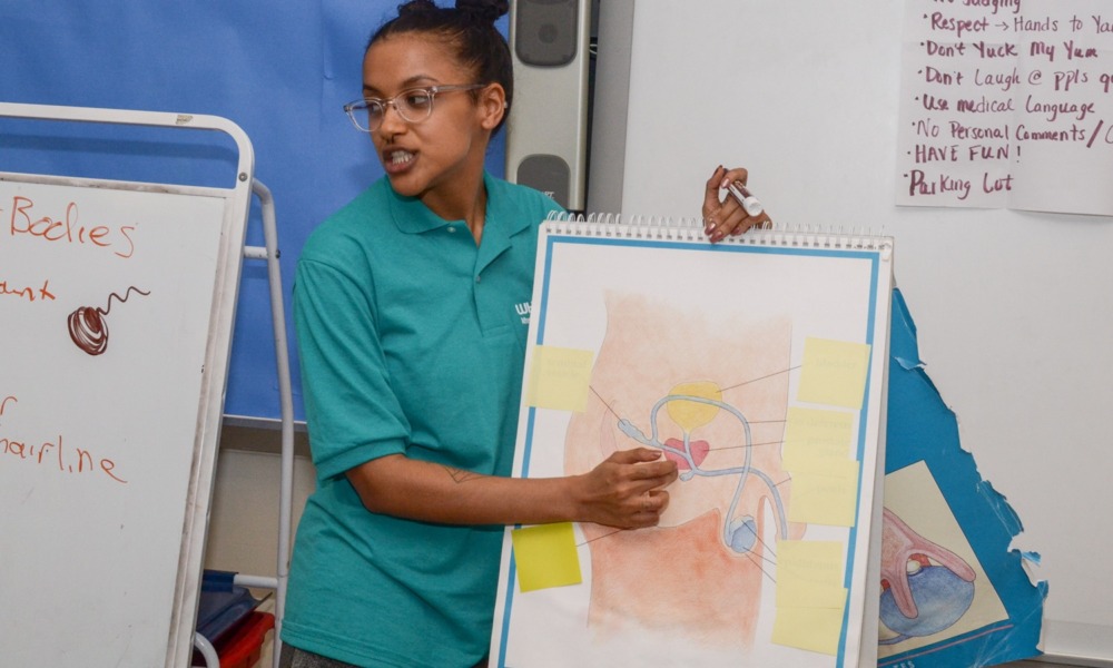 What I learned teaching sex education as a teen, and why every school needs it_feature: young woman points to diagram of sexual organs in front of classroom
