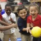 Joy, partnership and play create belonging and increase attendance_feature: recess, group of very happy children playing game with yellow ball