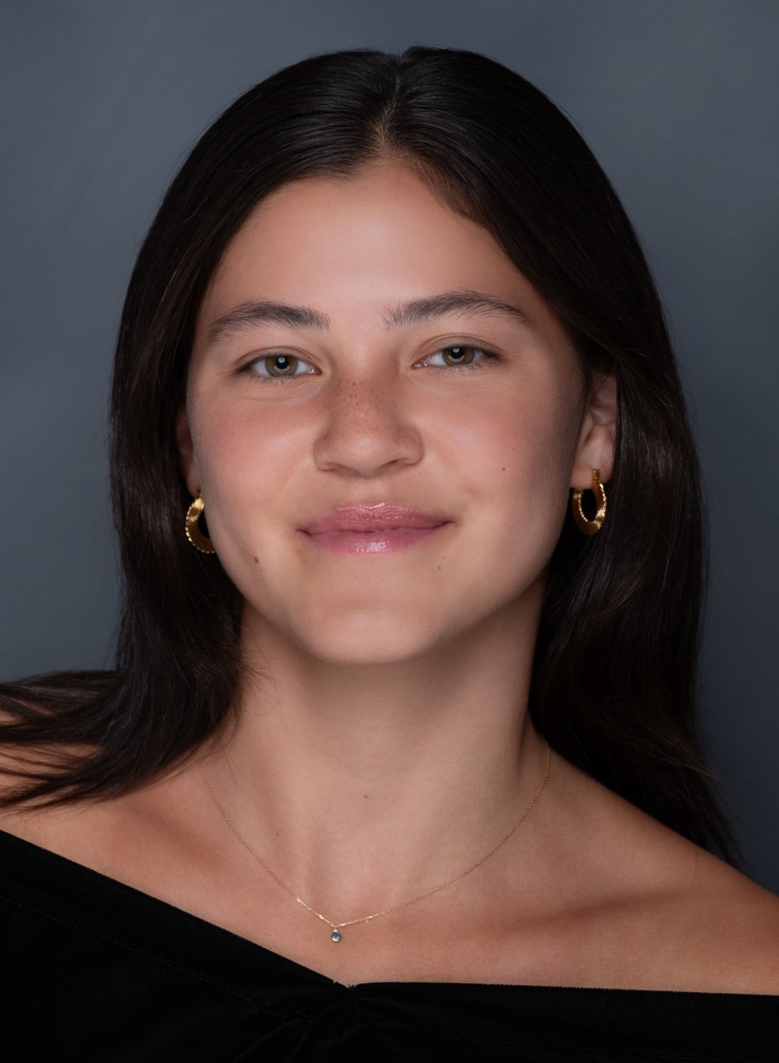 Mira Mikulka headshot: young woman with long dark hair wearing off-the-shoulder shirt in front of grey background