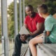 On developmental relationships _feature: black coach or mentor and white male student sit on bleachers and talk
