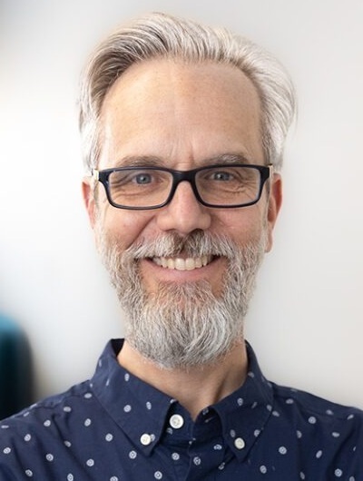 جودة برنامج الشباب، صورة توماس أكيفا: رجل أبيض ذو شعر رمادي وأبيض ولحية ويرتدي نظارة ذات إطار أسود