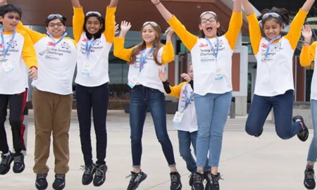 Young scientist challenge project award grants: group of youths in matching shirts and lanyards jumping for joy outdoors