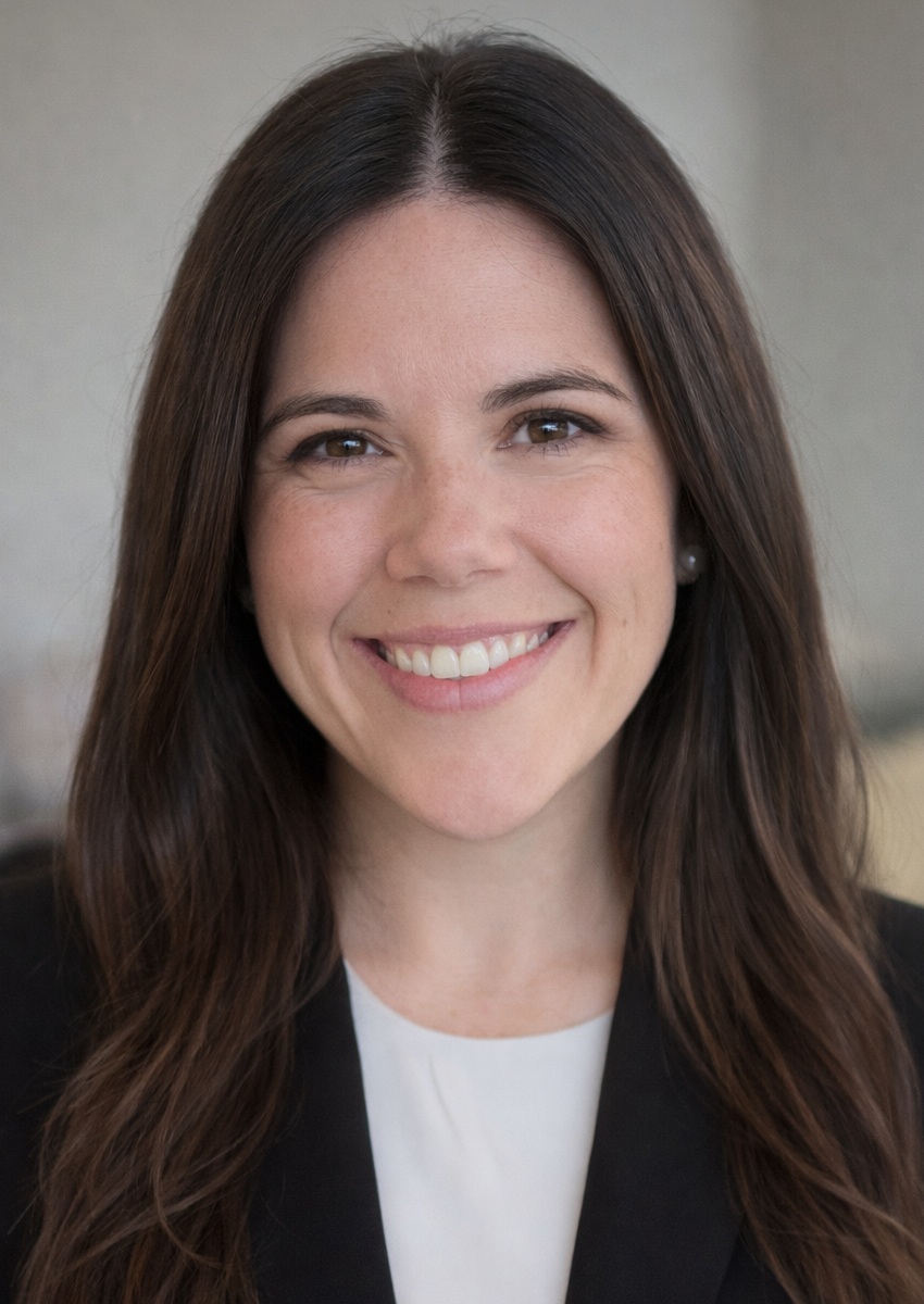 Ashley Boal headshot: white woman with long brown hair in dark blazer and white shirt smiling