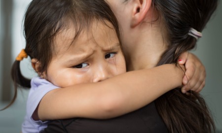 Child safety was never meant to look like this_feature: A sad little girl hugging her parent to feel safe, tearful.