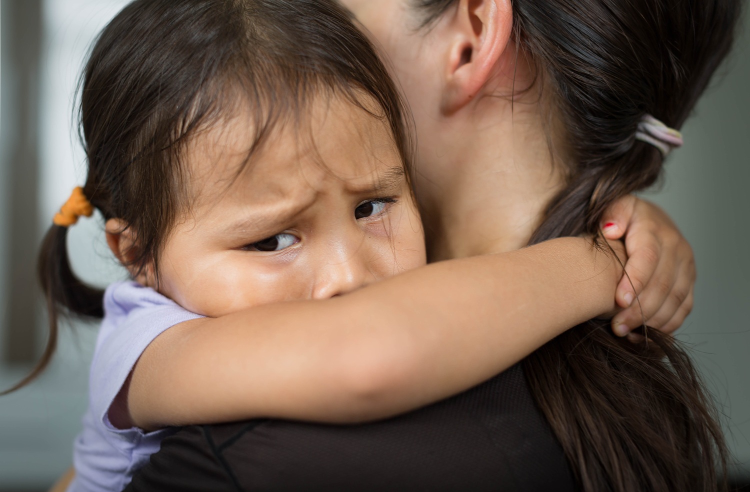 Child safety was never meant to look like this_feature: A sad little girl hugging her parent to feel safe, tearful.