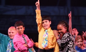 Youth dance builds the skills young people need_I credit dance with my pursuit of medicine_feature: group of children dancing on stage, some with arm raised and finger pointing up