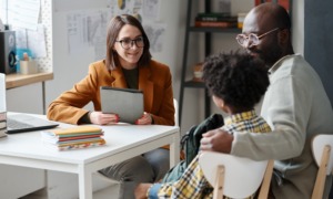 To fix student chronic absenteeism schools ust support families first_feature: Young teacher having meeting with parent of schoolboy, they sitting at table and talking together after lessons