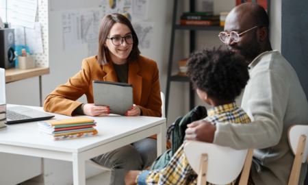To fix student chronic absenteeism schools ust support families first_feature: Young teacher having meeting with parent of schoolboy, they sitting at table and talking together after lessons