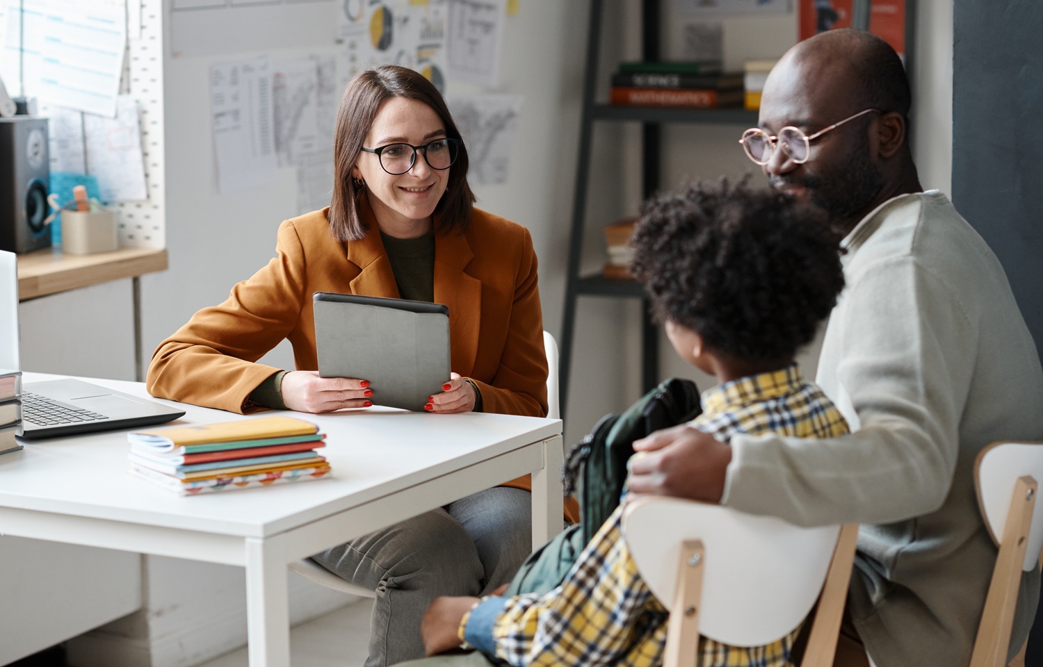 To fix student chronic absenteeism schools ust support families first_feature: Young teacher having meeting with parent of schoolboy, they sitting at table and talking together after lessons