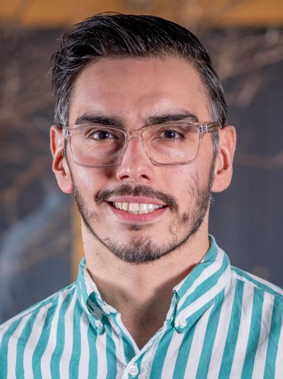 Daniel Hatcher headshot: white man with glasses and short dark hair wearing vertical-striped collared shirt