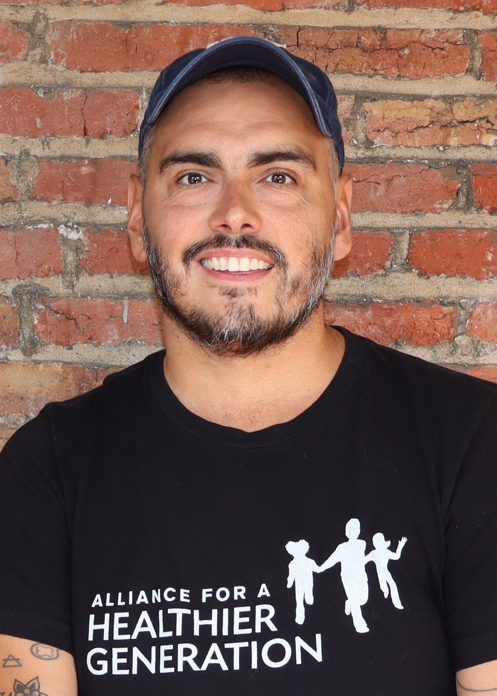Daniel Hatcher headshot: white man in hat wearing black t-shirt with white lettering