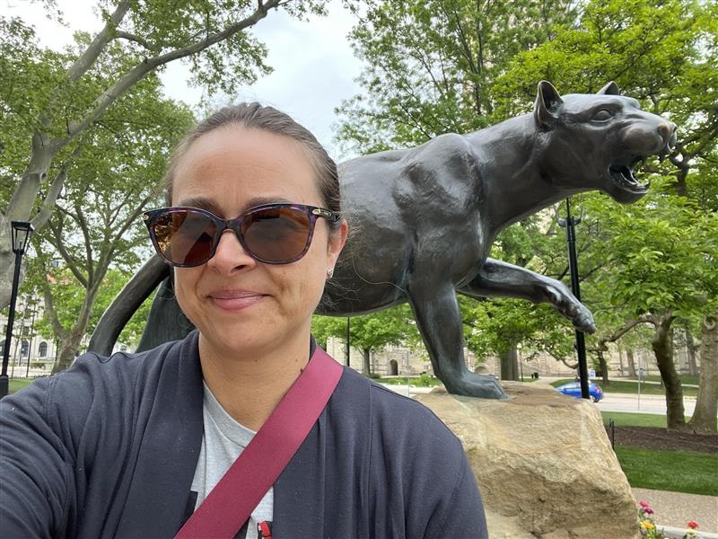 Katherine Plog Martinez selfie: Woman with sunglasses on and pulled back hair taking selfie in front of panther statue