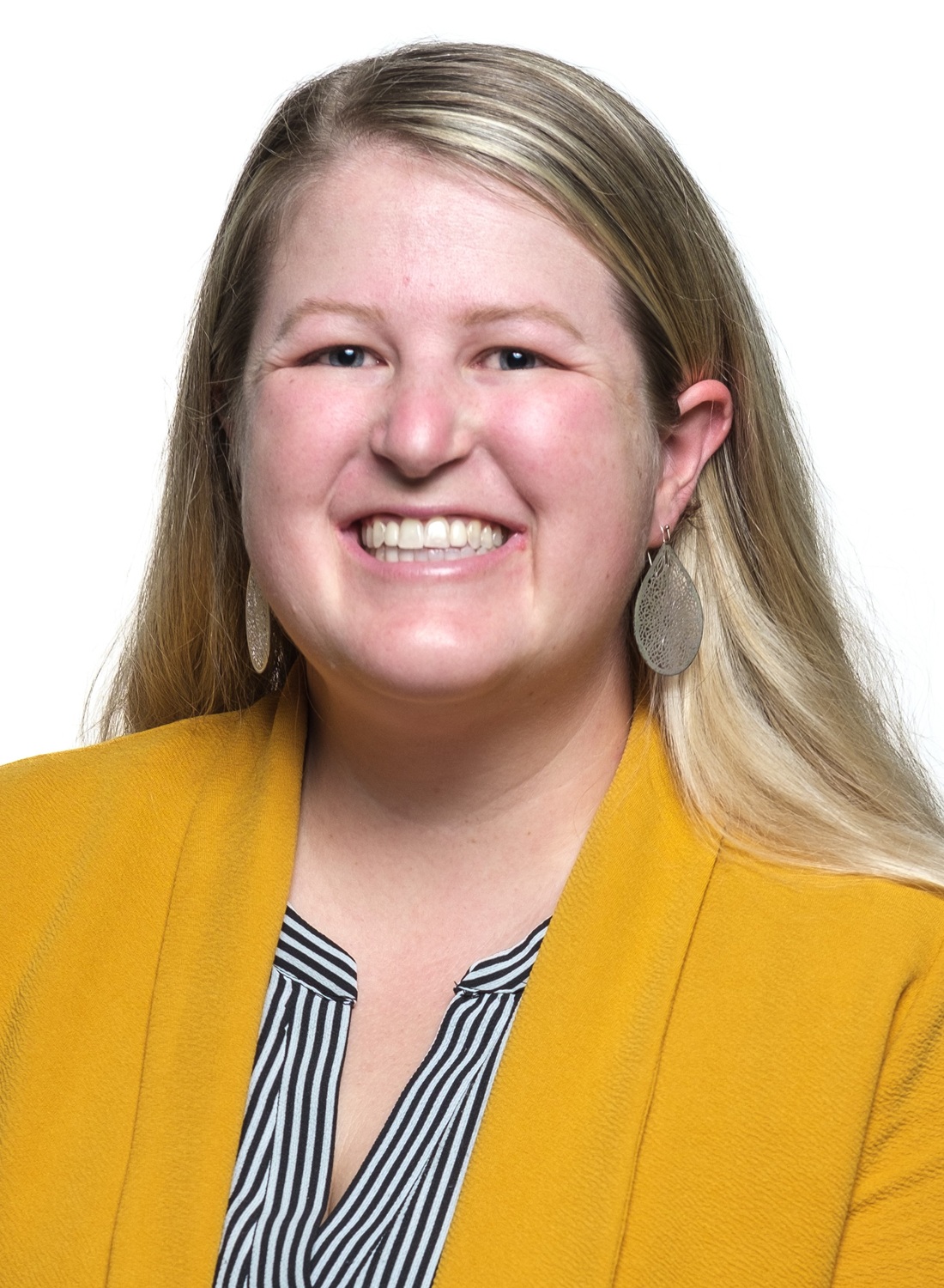 Molly Bernard headshot: young white woman with long blonde hair in yellow-orange blazer and striped shirt against white background