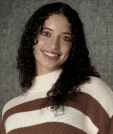 Tiffany Perera headshot: young woman with long culry black hair wearing horizontal-striped sweater