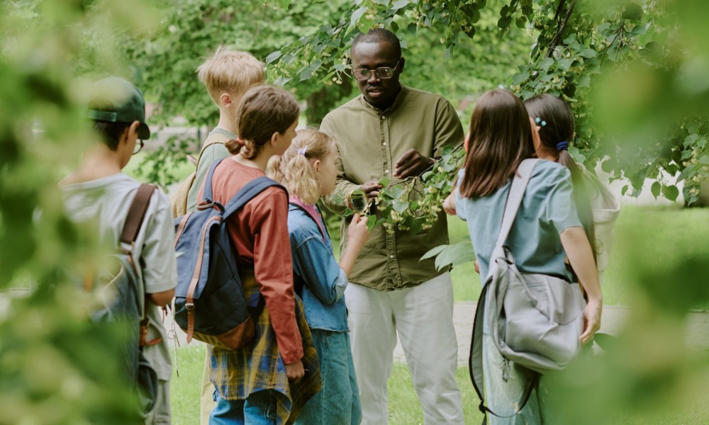 learning environments What John King's teachers were actually doing_feature: group of students listens to black male teacher outdoors teaching them about plants
