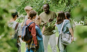learning environments What John King's teachers were actually doing_feature: group of students listens to black male teacher outdoors teaching them about plants