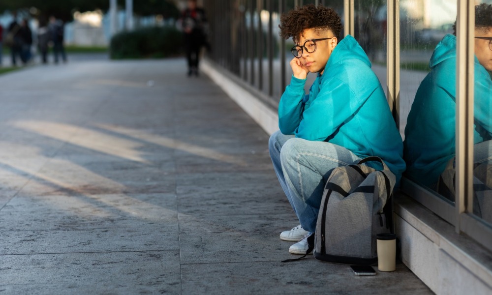 I lived in a coat closet to stay in college, student homelessness _feature: unhappy college student sits on sidewalk with backpack