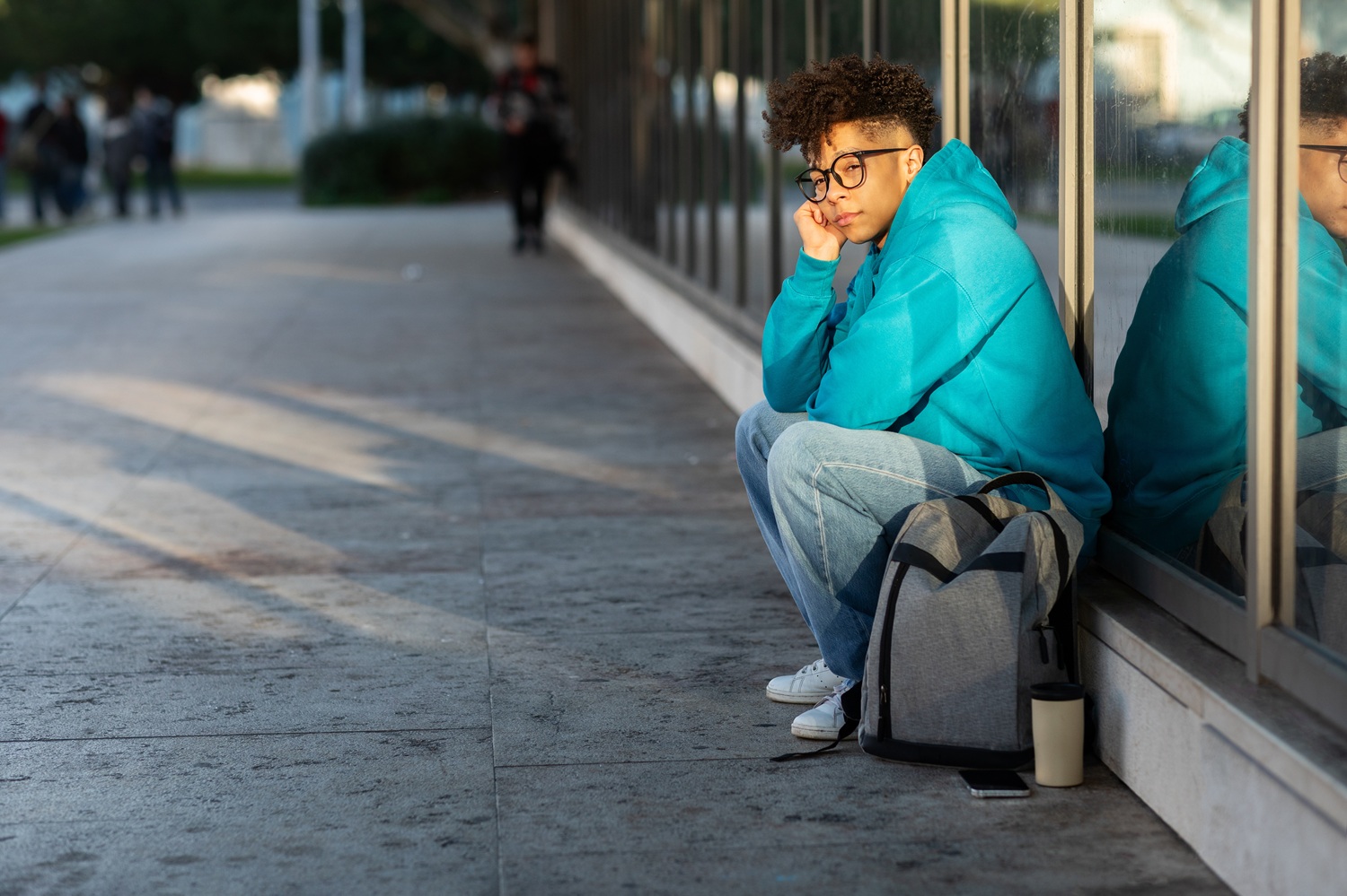 I lived in a coat closet to stay in college, student homelessness _feature: unhappy college student sits on sidewalk with backpack
