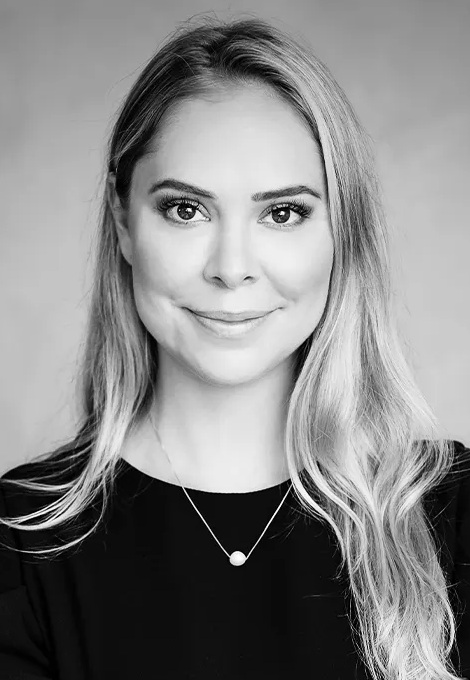 Jussara Negromonte headshot: woman with long blonde hair in front of grey background in grey-scale image