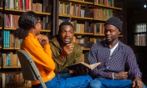 We're teaching skills but not purpose, meaning-making _The missing metric in youth development_feature: group of black youth discussing ideas in library setting while one holds a book open