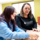 Nearly 200 student stories reveal what AI can’t replace- developmental Relationship _feature: white woman with glasses helps young girl with classwork