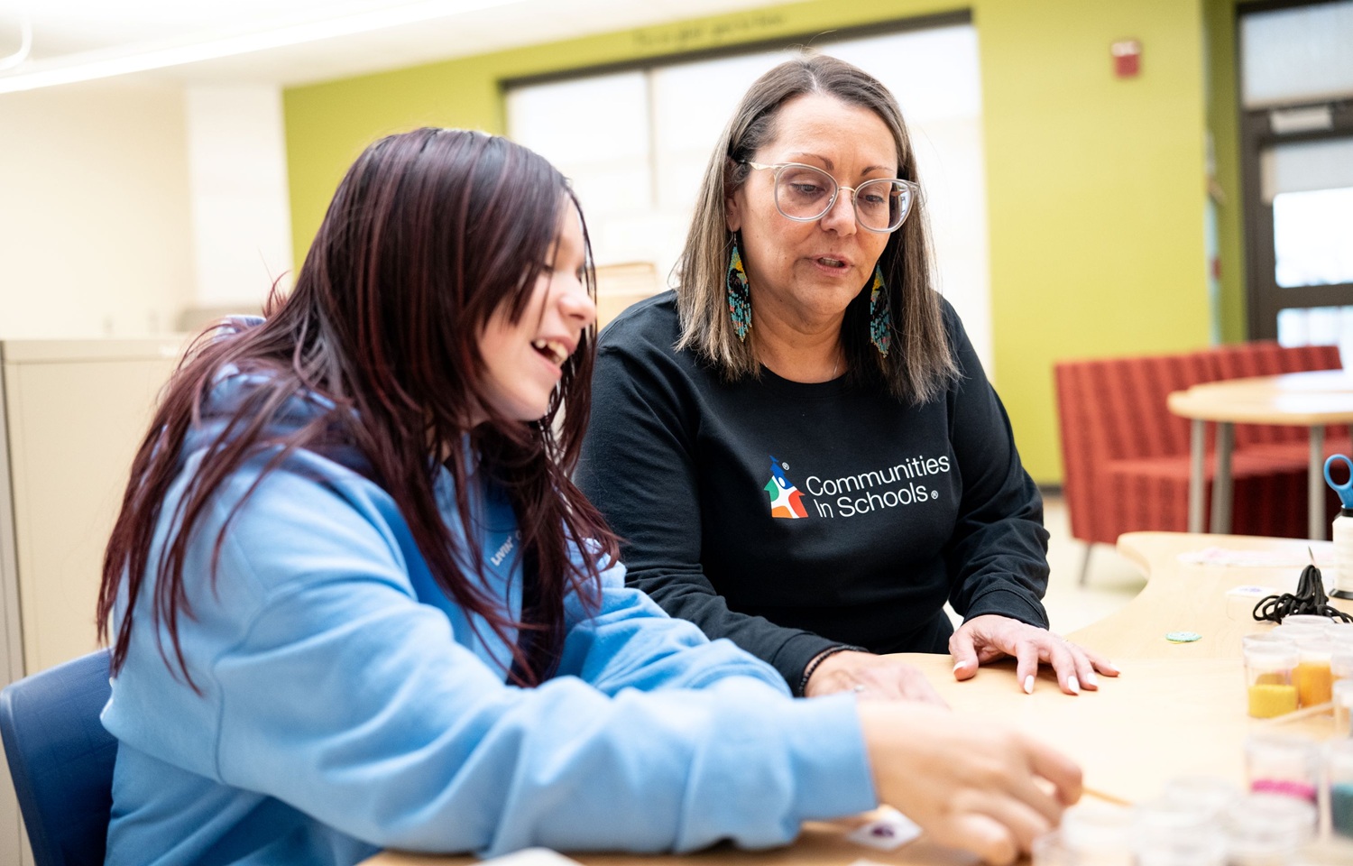 Nearly 200 student stories reveal what AI can’t replace- developmental Relationship _feature: white woman with glasses helps young girl with classwork