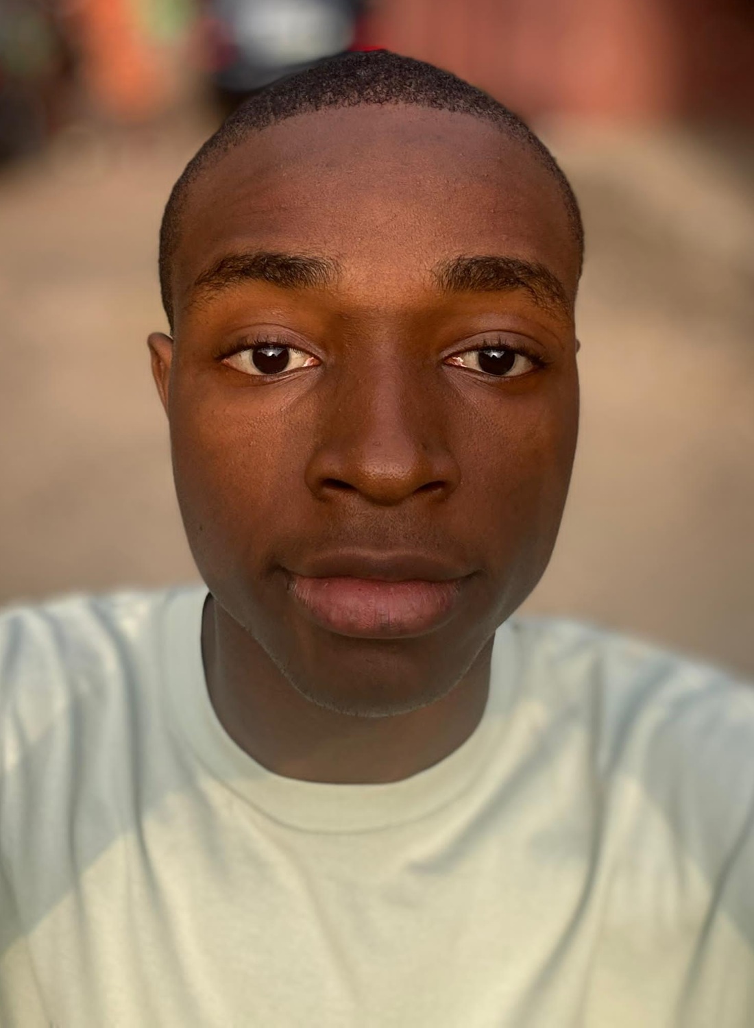 Emerole Clinton headshot: selfie of young black man with short hair in white shirt
