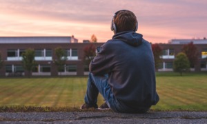 I was that kid-and schools are still getting it wrong_feature: young male teen sitting and looking at school with headphones on