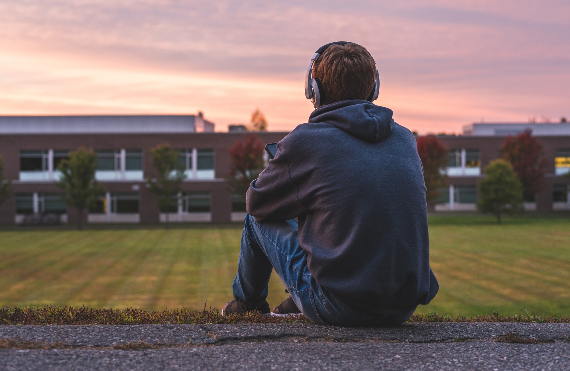 I was that kid-and schools are still getting it wrong_feature: young male teen sitting and looking at school with headphones on