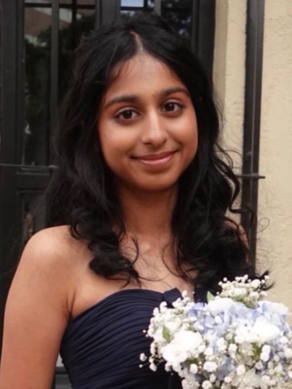 Siri Merugu headshot: young woman with long dark hair holding bouquet of flowers