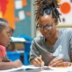 What if we treat staff development as part of our core mission_feature: young black woman helps two young black children at table in youth program