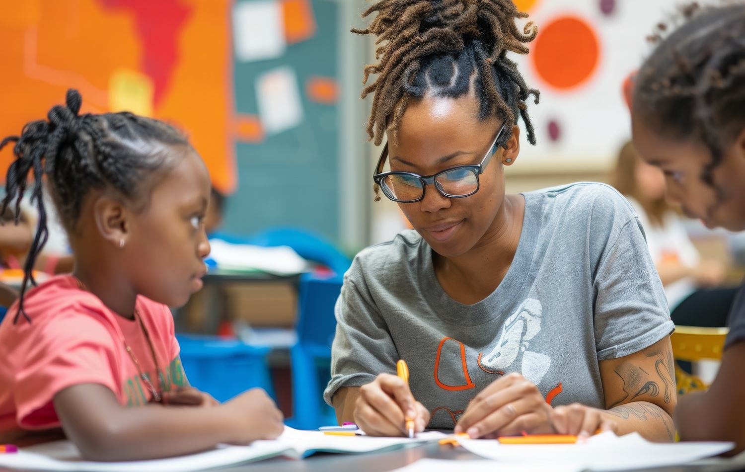 What if we treat staff development as part of our core mission_feature: young black woman helps two young black children at table in youth program