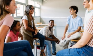 What kind of developmental environments help young people become fully human_feature: group of young people in classroom after hours talking to educator