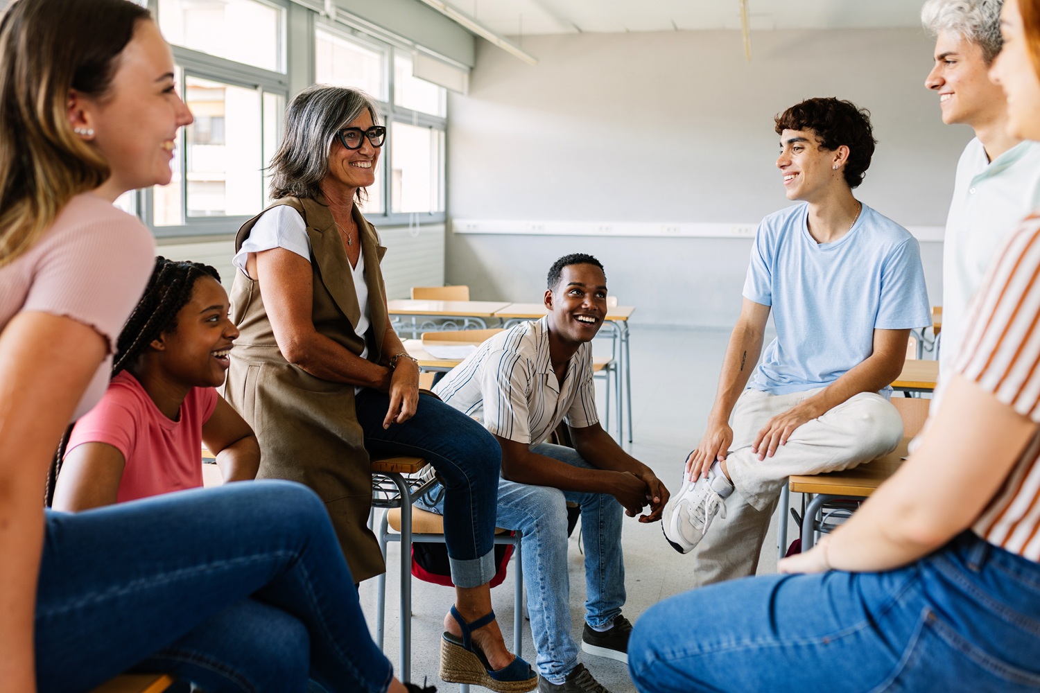 What kind of developmental environments help young people become fully human_feature: group of young people in classroom after hours talking to educator