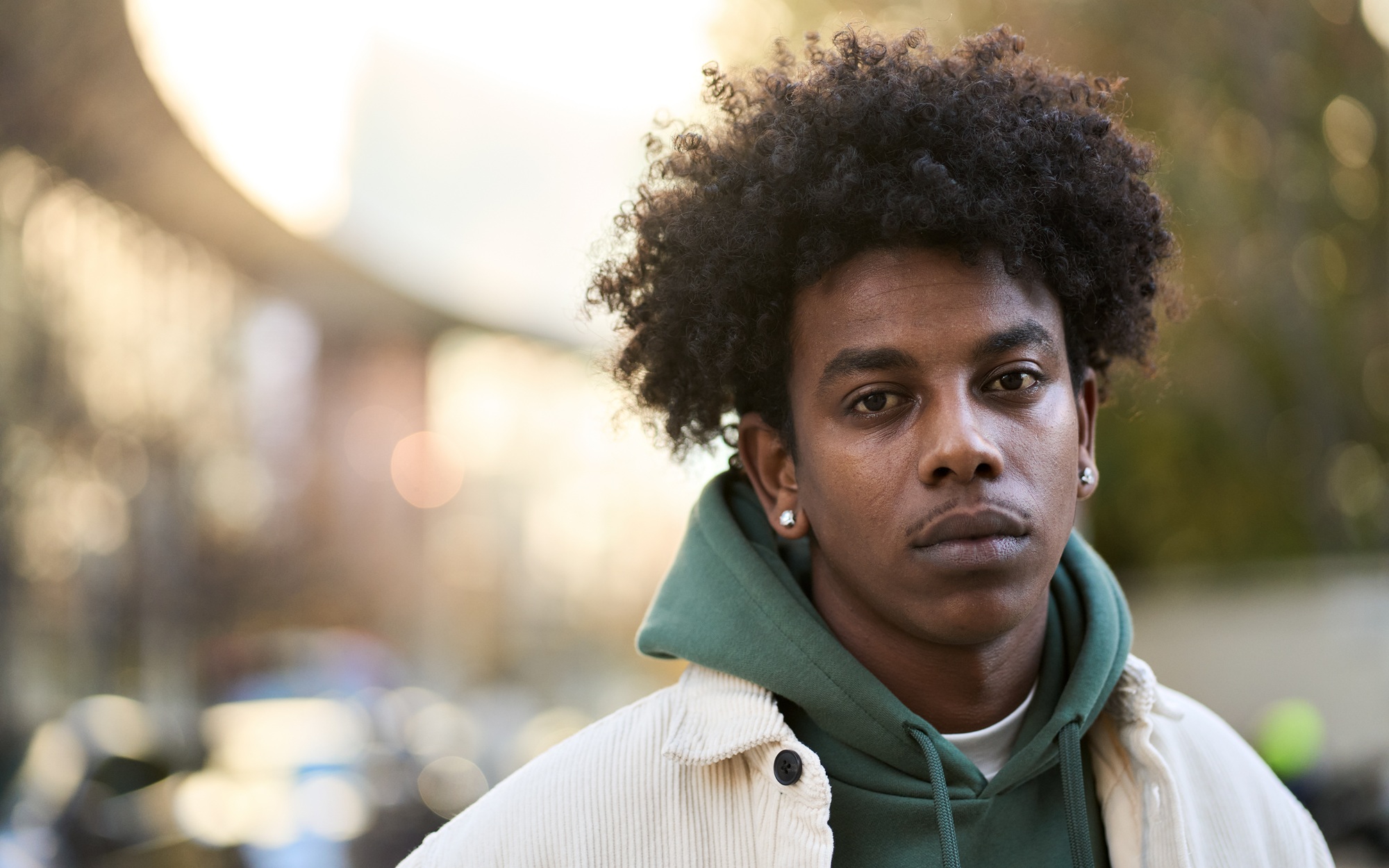 Young people aren't losing trust-they're giving up_feature: young black man in hoodie and jacket outdoors looking sad and disappointed