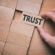 Exploring the trust gap-An open invitation_feature: Trust word written on wooden block. Building trust business concept.