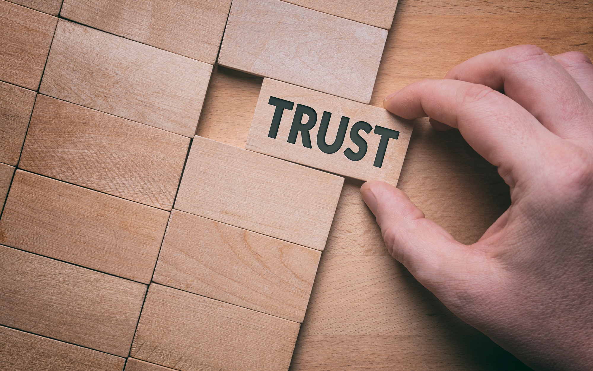 Exploring the trust gap-An open invitation_feature: Trust word written on wooden block. Building trust business concept.